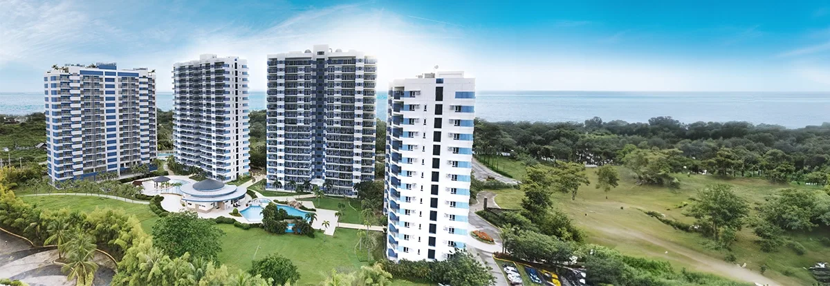 Aerial view of the four AmiSa Private Residences towers beside landscaped grounds and the Mactan coastline